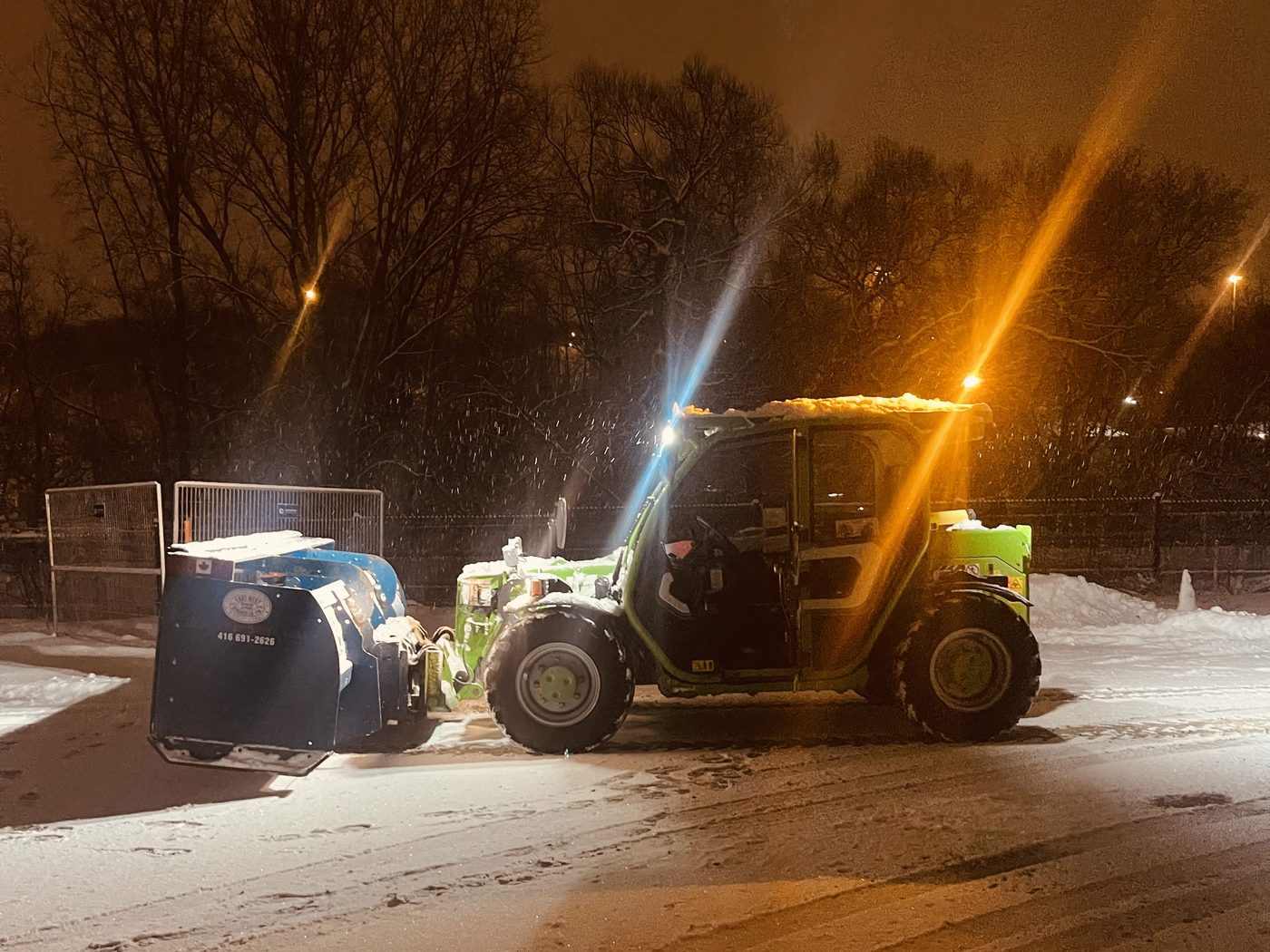 East-West loader clearing and relocating snow overnight under street lighting during a Toronto storm